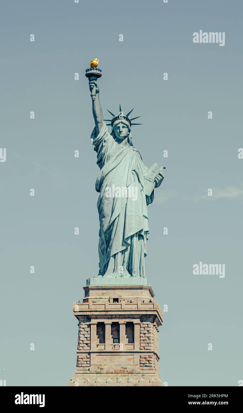 The iconic Statue of Liberty against a blue sky, providing a breathtaking view of its immense size and grandeur Stock Photo