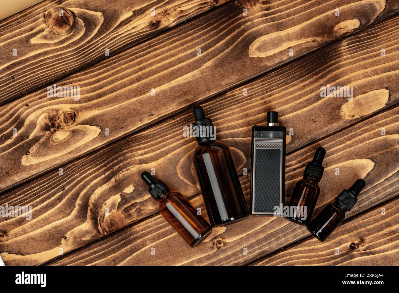 Vape and vape juice bottles on brown wooden background Stock Photo