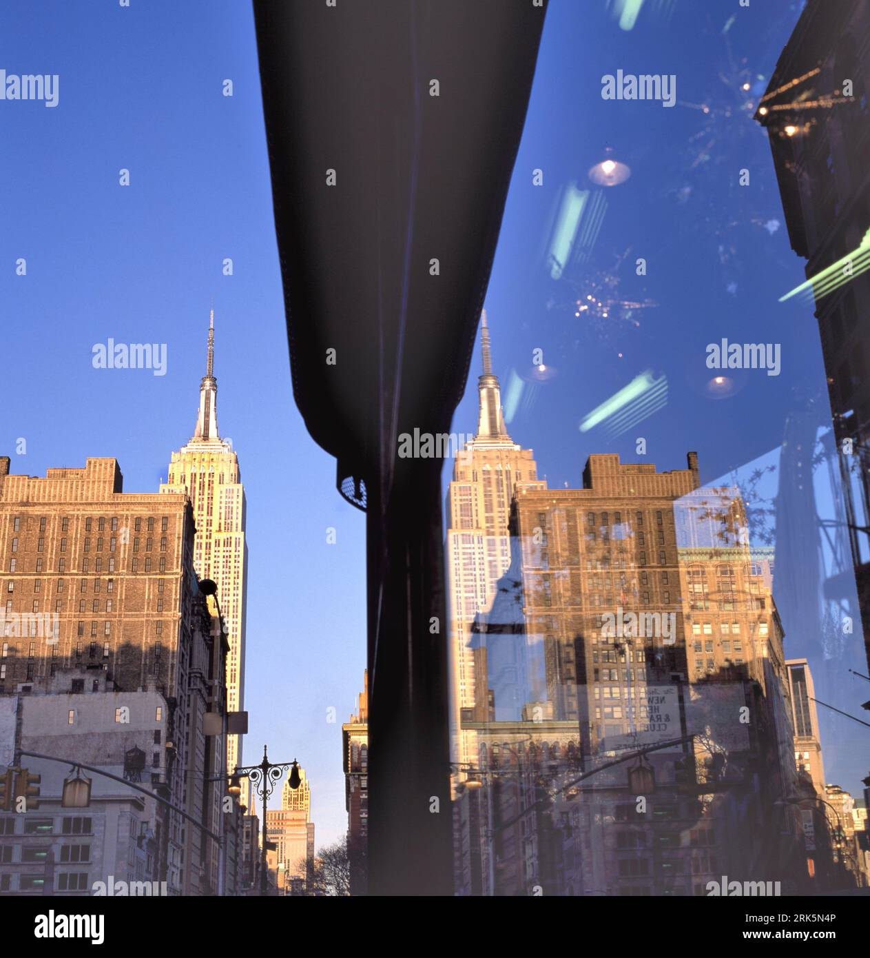 View looking up of the Empire State Building, with reflection in the window of a building in the same street, New York City, USA. Stock Photo