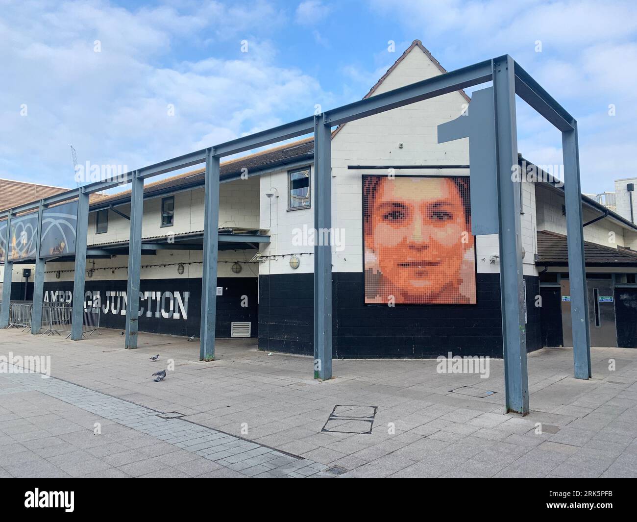 A face-shaped portrait hangs on the side of a building in the corner of Cambridge, United Kingdom Stock Photo