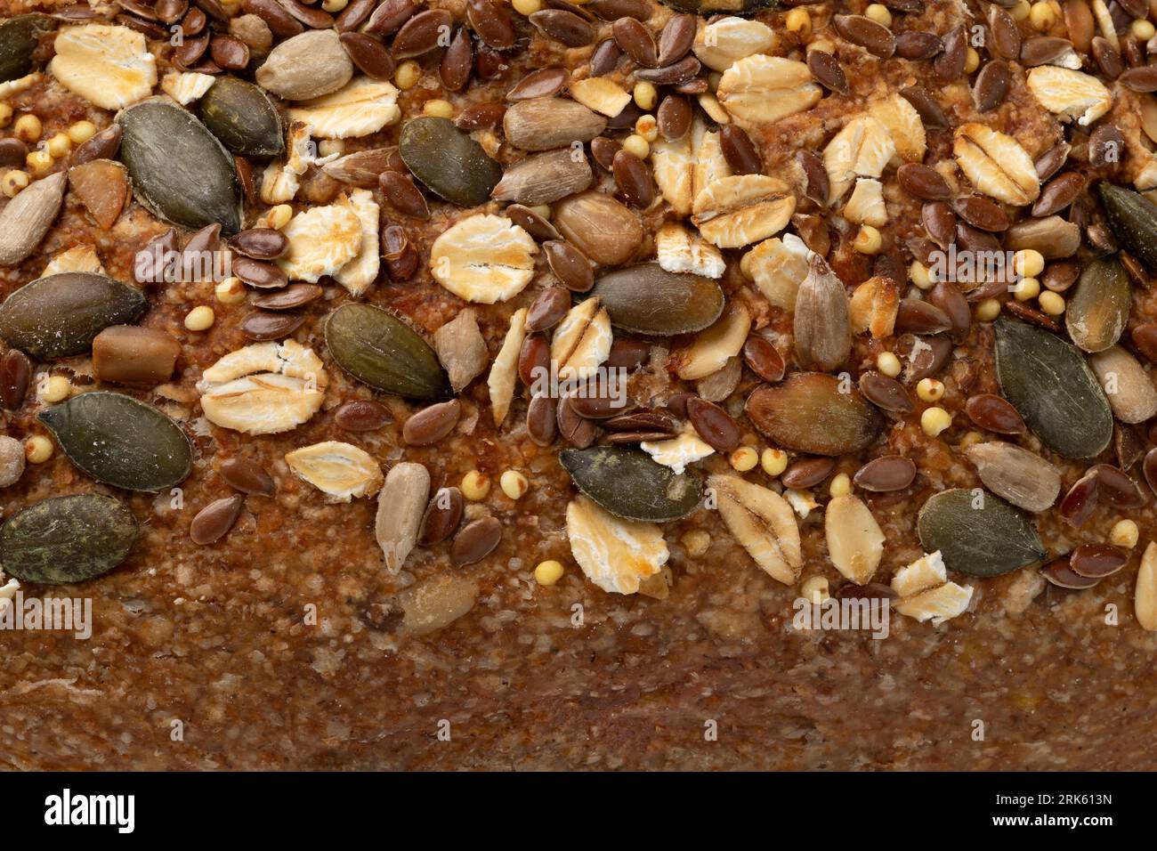 Side of a sourdough loaf of bread with a variation of seeds close up  as background Stock Photo