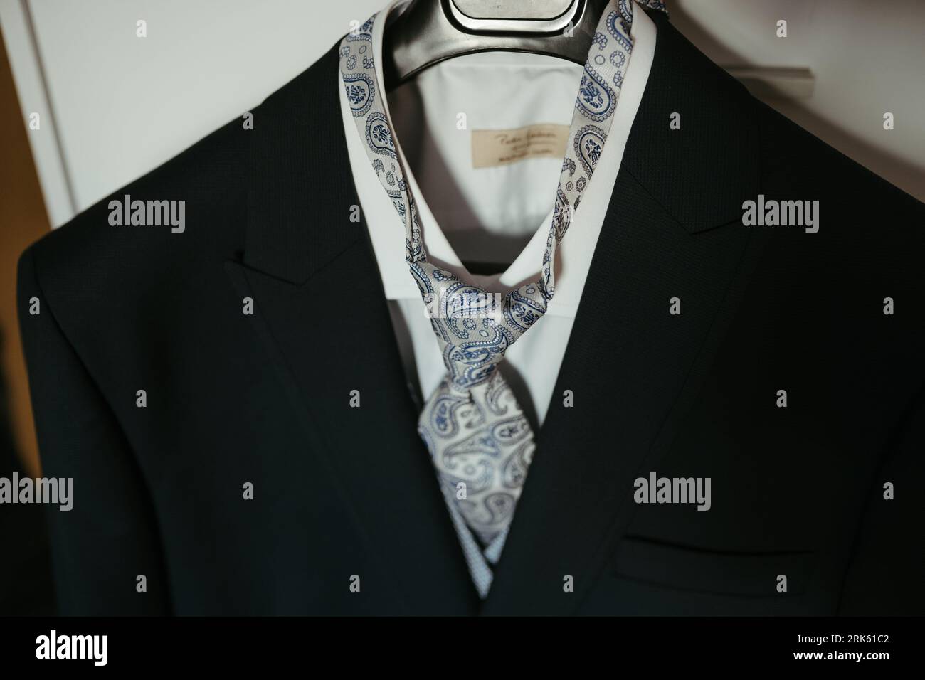 This stock photo features a formal outfit,  a suit, hung up in a doorway Stock Photo