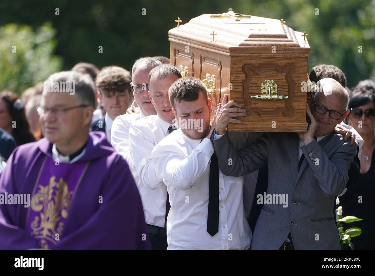 Father Gerry Boyle (left) walks in front of the coffin of Brendan Wall ...