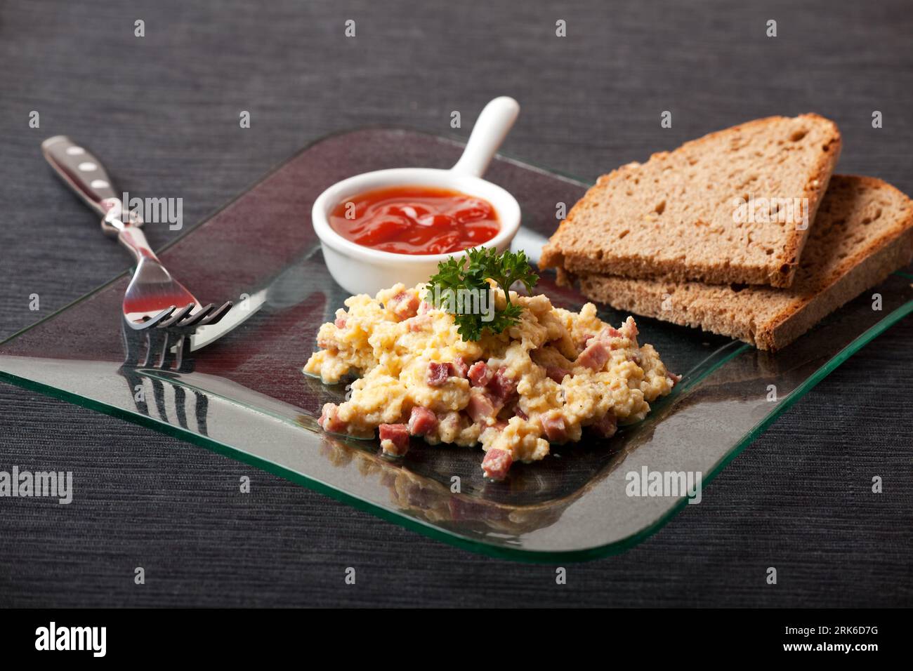 scambled eggs with ham cubes on a glass plate Stock Photo