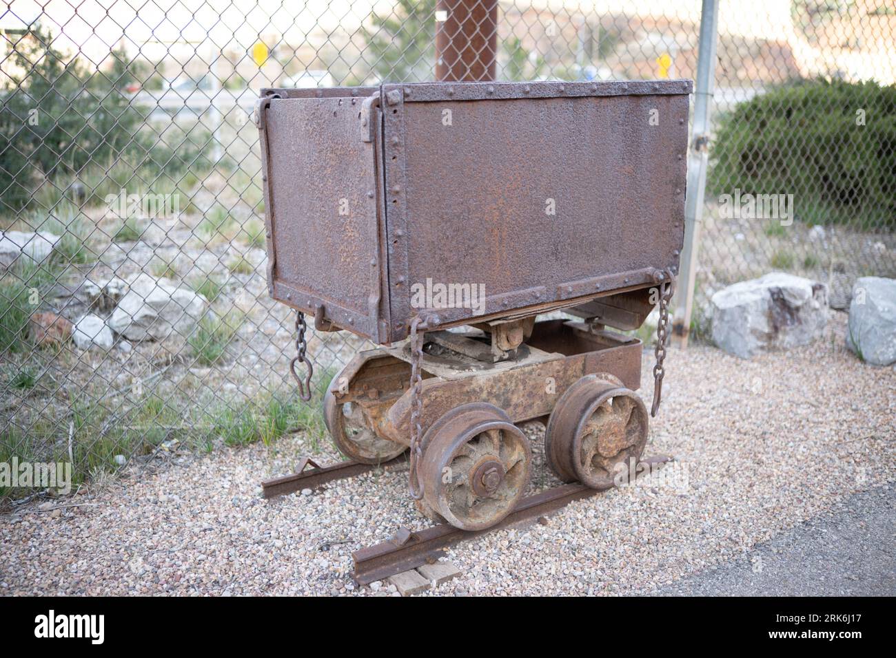 An antique railroad cart sits atop rail tracks, exhibiting signs of