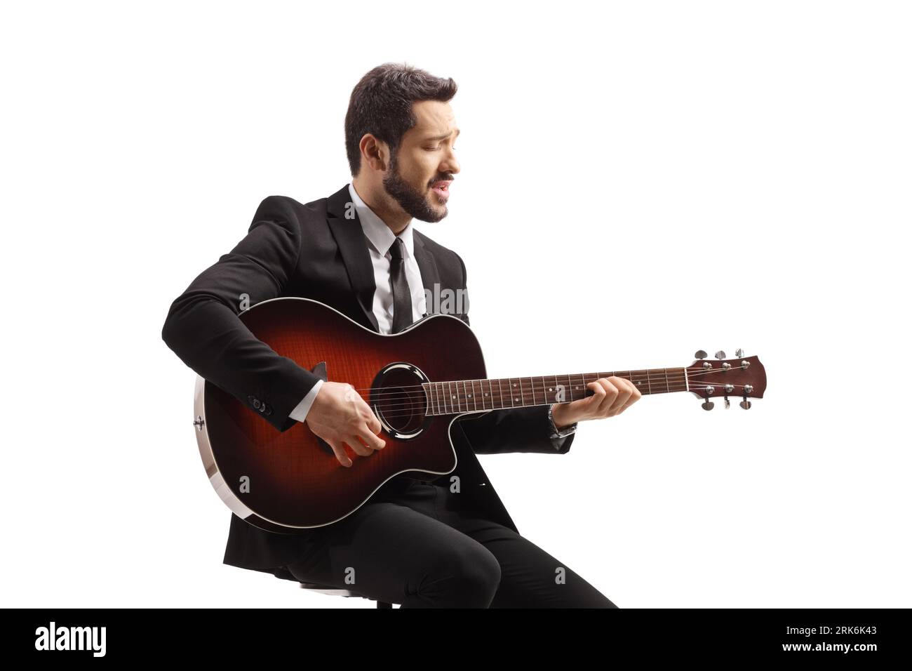 Musician with an acoustic guitar sitting on a chair and playing ...