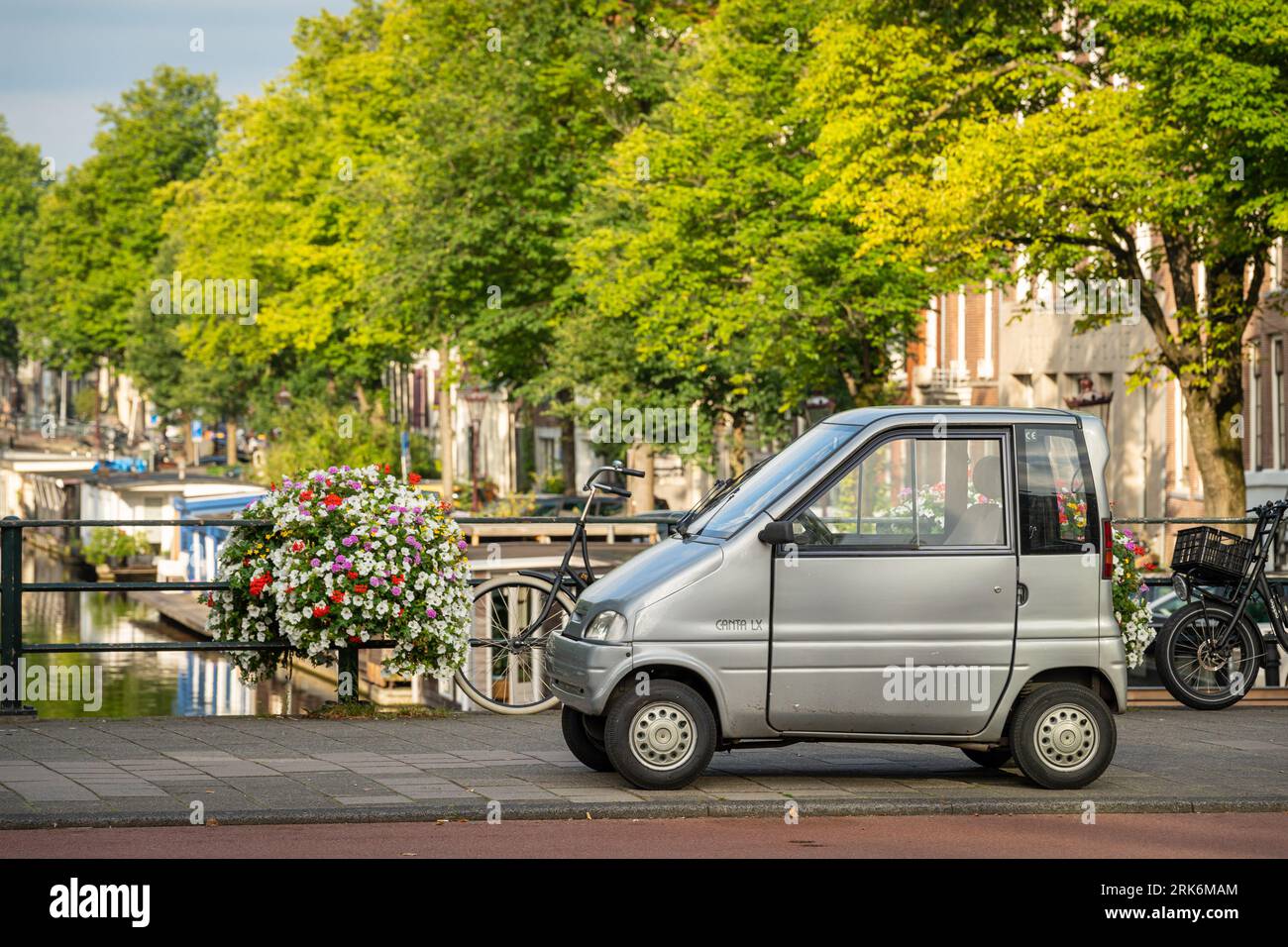 Amsterdam, The Netherlands, 24.08.2023, Dutch two-seat vehicle Canta LX, classified as mobility aid, parked at the bridge by the canal Stock Photo