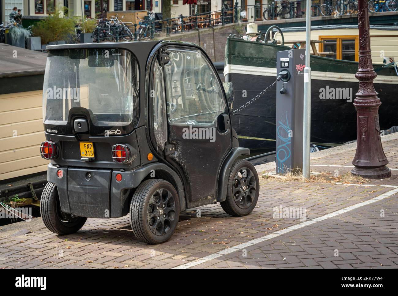 Amsterdam, The Netherlands, 24.08.2023, Electric microcar Estrima Biro, categorized also as light quadricycle moped, parked by the canal Stock Photo