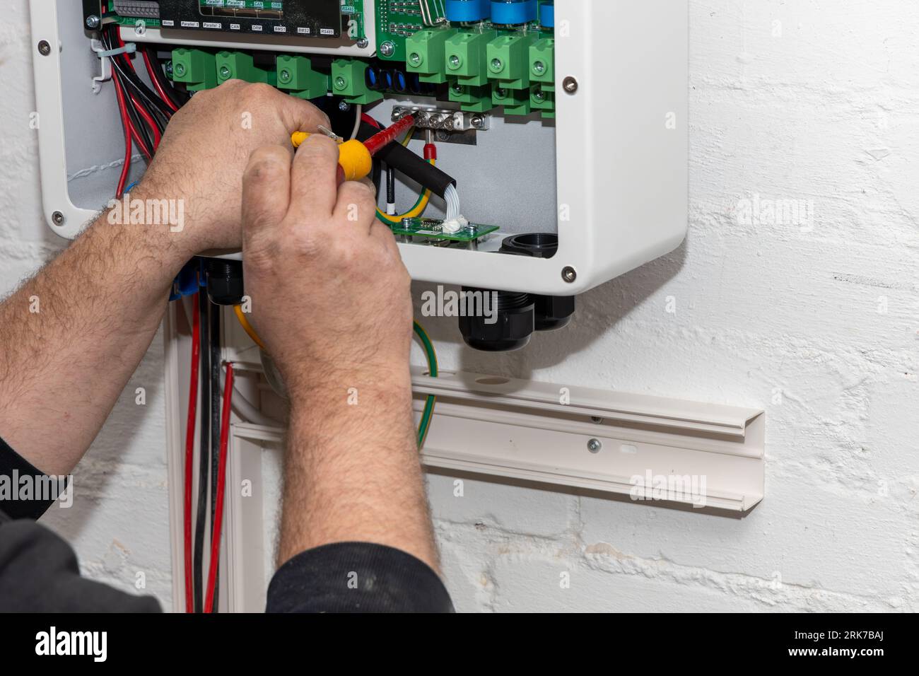 An electrician installs a new inverter and connects it to a photovoltaic system Stock Photo