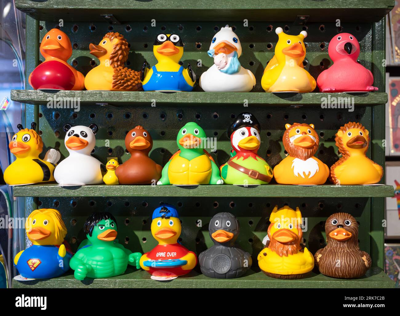 20 fun and colourful rubber ducks in different disguises including as superheroes lined up in three rows on shelves in a shop in Brighton, East Sussex Stock Photo