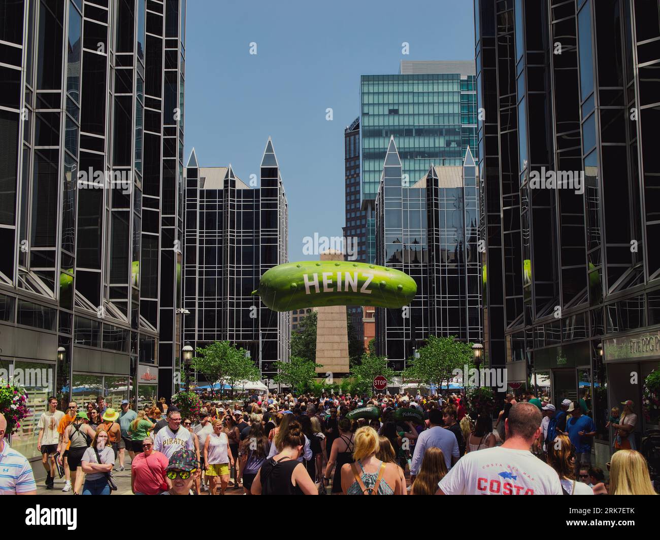 A Heinz pickle balloon floating above a large crowd of excited visitors