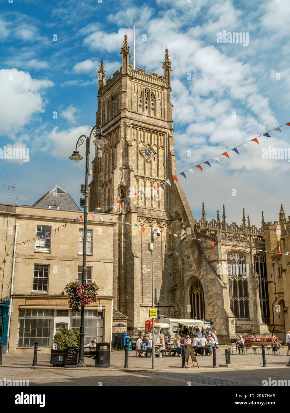 Cirencester, Gloucestershire - England. People sit and enjoy a snack in the late summer sunshine under the impressive tower of Cirencester Parish Chur Stock Photo