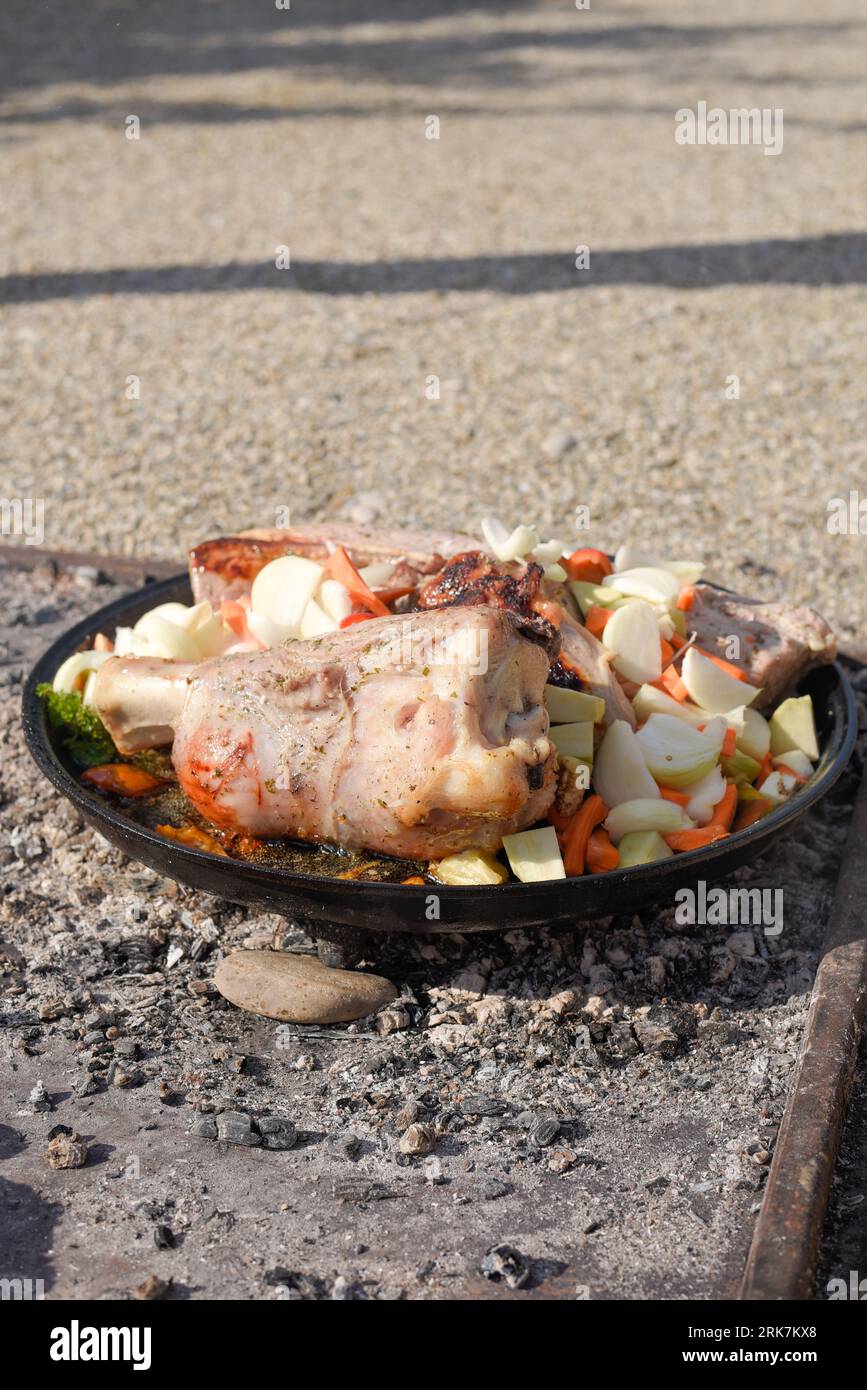 A charcoal pit with an assortment of marinated meats and vegetables being cooked over an open flame Stock Photo