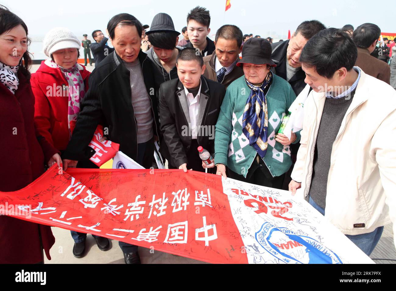 (100411) -- SHANGHAI, April 11, 2010 (Xinhua) -- People watch the team banner with staff signatures, aboard the Xuelong (Snow Dragon) icebreaker upon its arrival at the harbour of Shanghai, east China, April 10, 2010. China s 26th Antarctic expedition team aboard the Xuelong (Snow Dragon) icebreaker return to its base in Shanghai Saturday morning after finishing 12 scientific research projects covering remote sensing, icebergs, biology, physics, etc. This expedition had the biggest staff since China started Antarctic missions in 1984. The 249 staff completed more than 50 scientific research pr Stock Photo