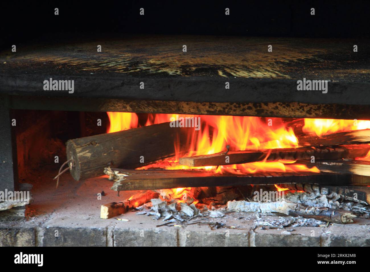 A rustic wood-fired oven resting on a natural stone hearth Stock Photo