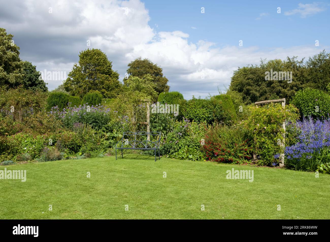 attractive metal bench in a beautiful English country garden at