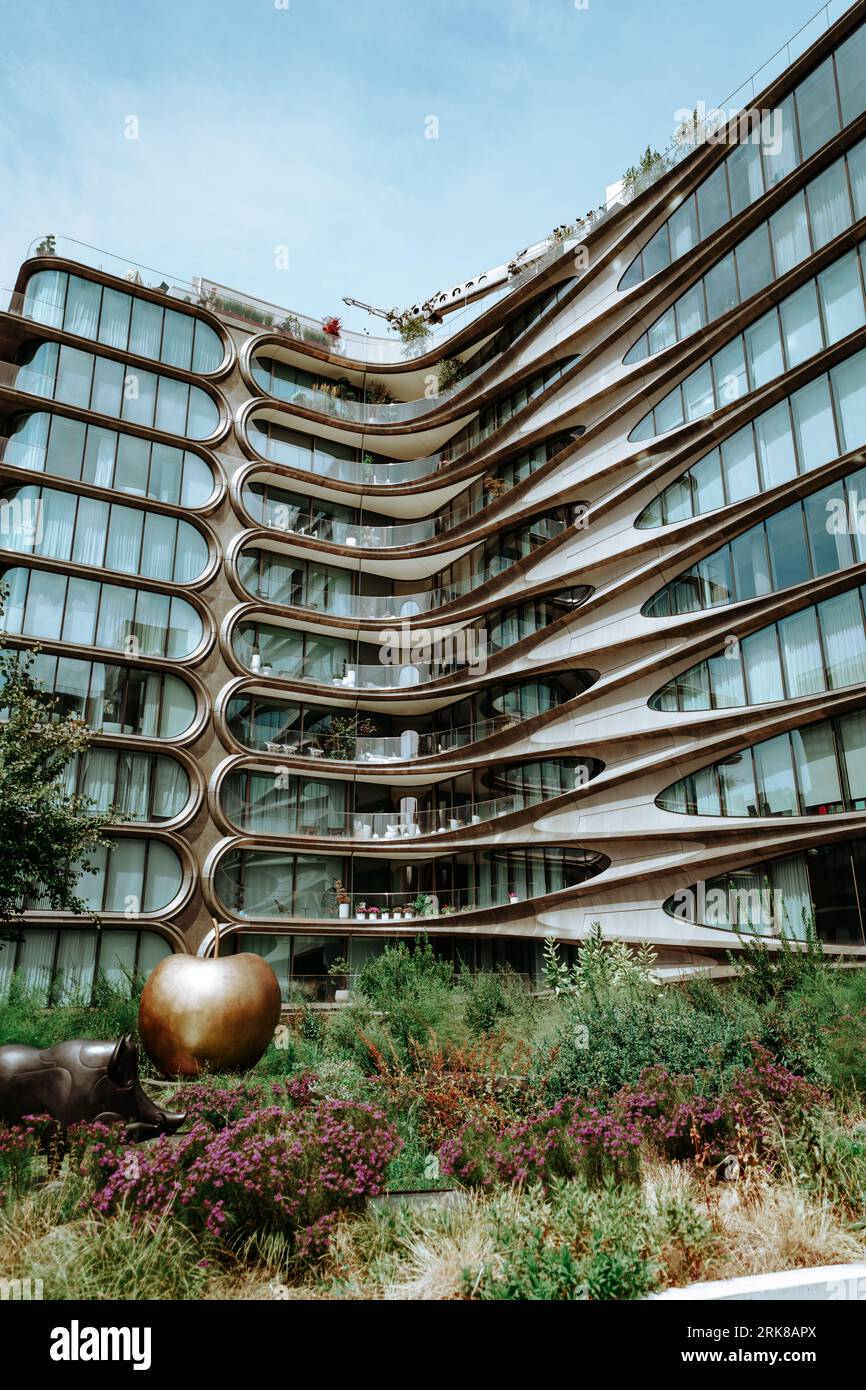 A bronze sculpture of an apple sits in front of a contemporary building ...