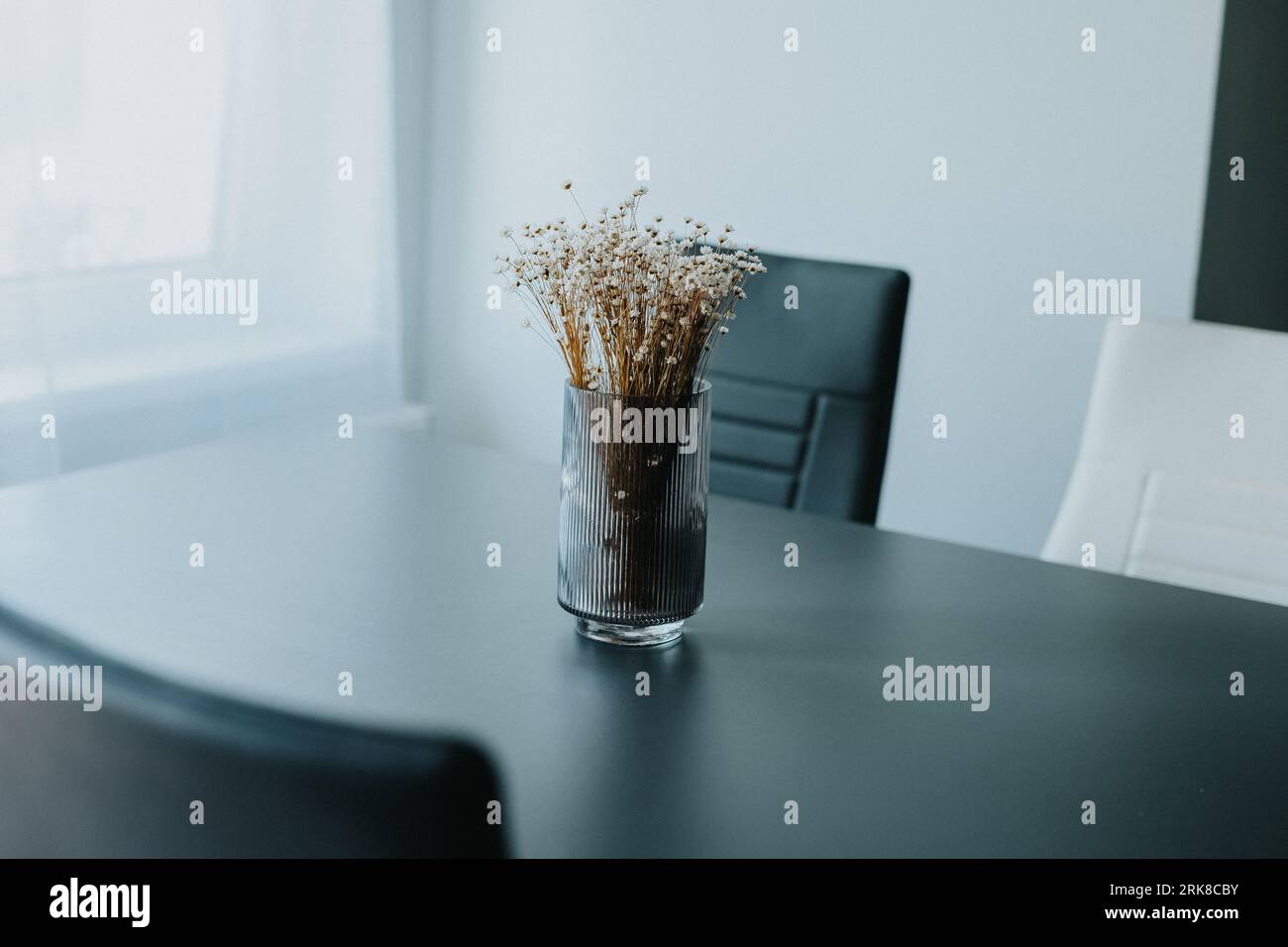 A dining room table featuring an arrangement of dried grasses and assorted flowers in a decorative vase Stock Photo