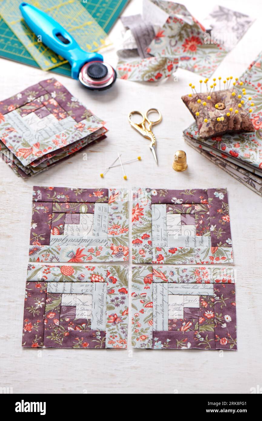 Patchwork log cabin blocks, stack of blocks, sewing accessories on white wooden surface Stock Photo