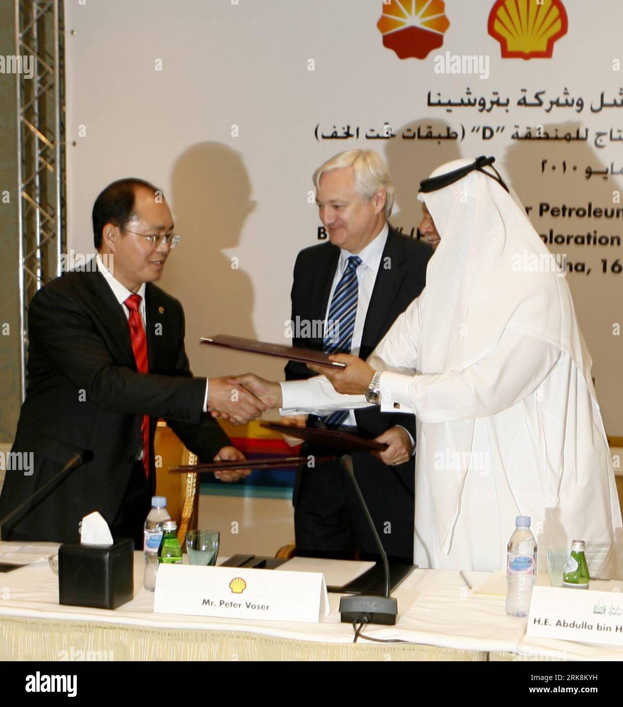 Bildnummer: 54052731  Datum: 16.05.2010  Copyright: imago/Xinhua (100517) -- QATAR, May 17, 2010 (Xinhua) -- Zhao Dong (L), CFO of PetroChina International Investment, exchanges the agreement documents with Abdulla Bin Hamad Al-Attiyah (R), deputy premier and minister of Energy and Industry of Qatar, while Peter Voser (C), CEO of Royal Dutch Shell Plc, looks on during the signing of The Exploration and Production Sharing Agreement (EPSA) in Doha, May 16, 2010. The EPSA is signed Sunday between Qatar Petroleum (QP) and joint partners Shell and China National Petroleum Corporation (CNPC) for the Stock Photo