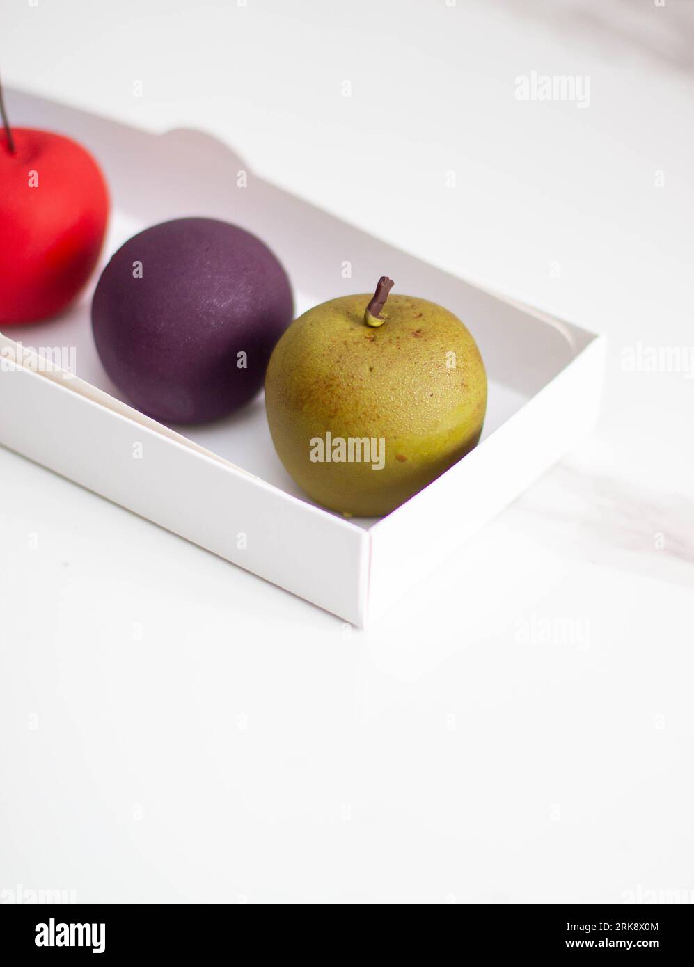 Modern realistic fruit pastries made of chocolate and mousse. Red apple, green apple, blueberry and passion fruit for cafe or restaurant Stock Photo