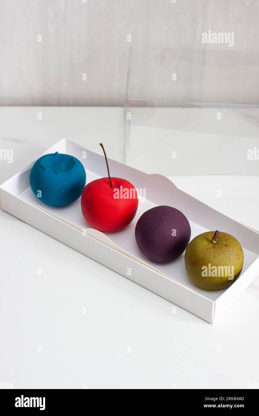 Modern realistic fruit pastries made of chocolate and mousse. Red apple, green apple, blueberry and passion fruit for cafe or restaurant Stock Photo