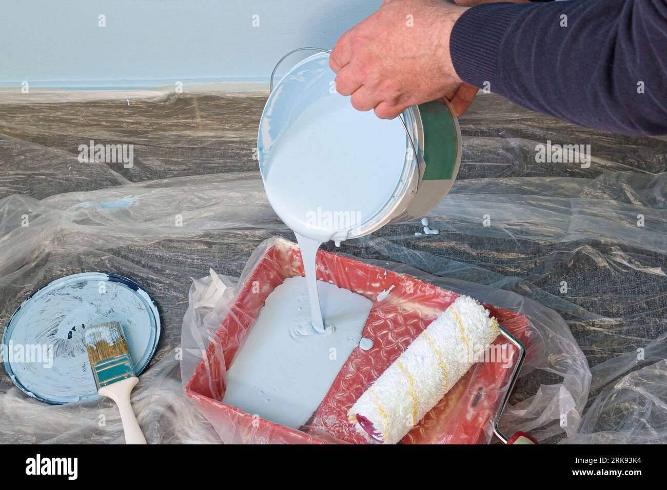 Filling the paint roller tray with paint. Painting the walls with a roller Stock Photo Alamy