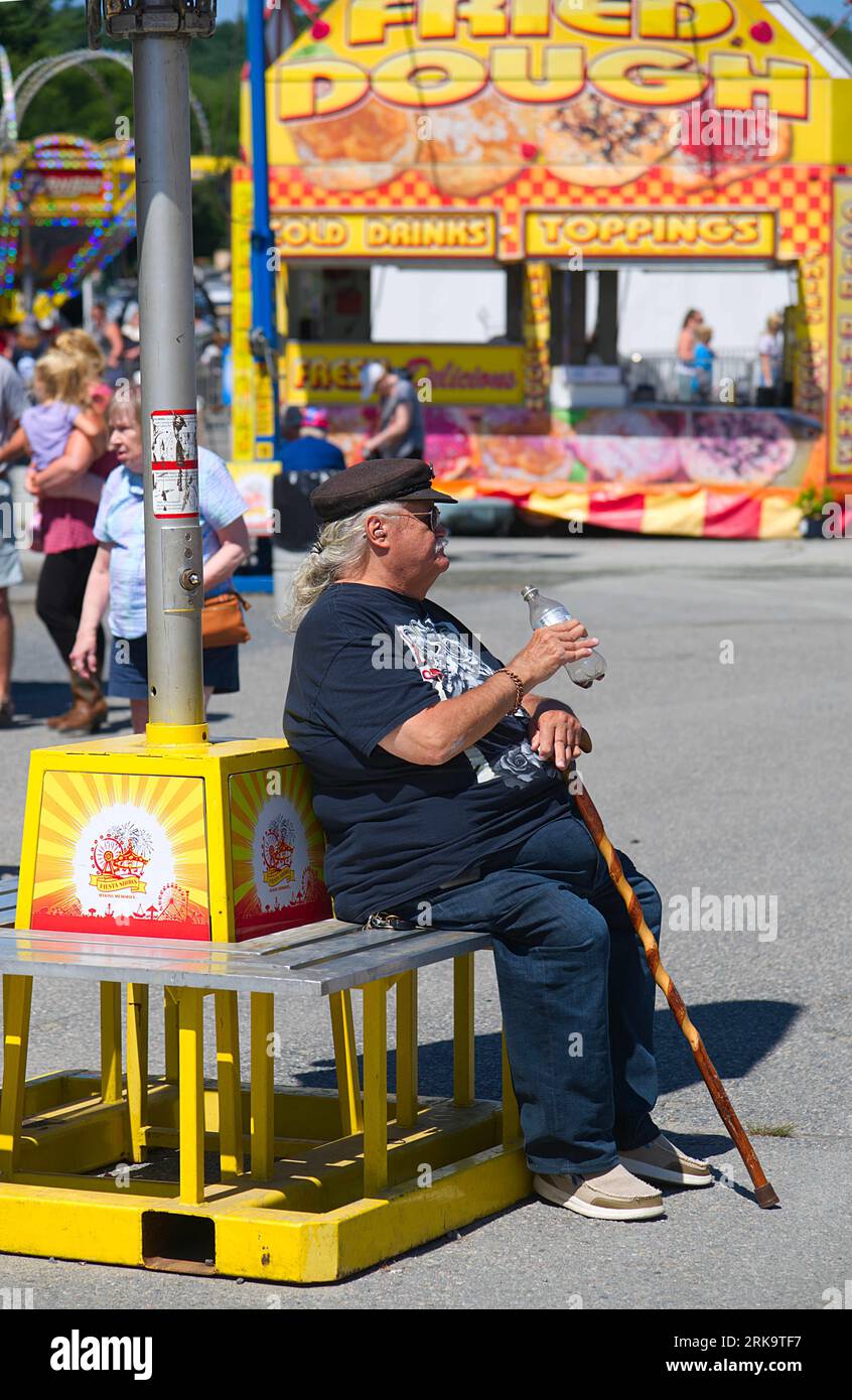 A senior citizen takes a break at the Marshfield Fair.  Marshfield, Massachusetts, USA Stock Photo