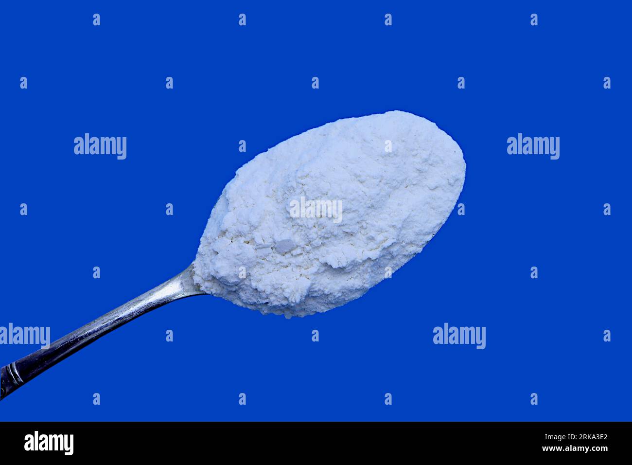 Home baking ingredients: Still life of plain white flour. Blue background, negative space. Stock Photo