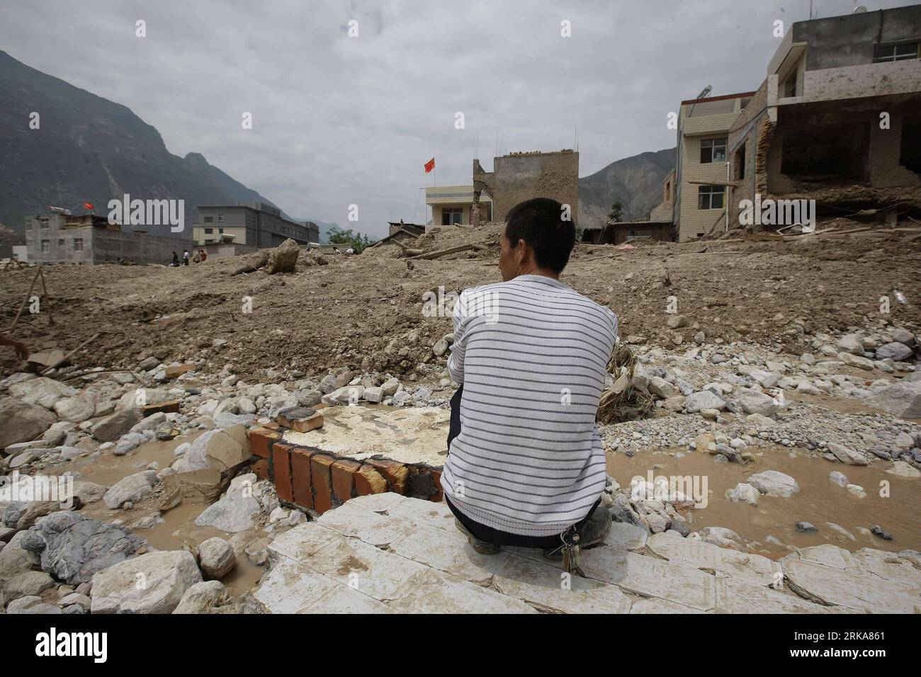 Bildnummer: 54284968  Datum: 09.08.2010  Copyright: imago/Xinhua ZHOUQU, Aug. 9, 2010 (Xinhua) -- A man rests on a piece of collapsed wall in landslide-hit Zhouqu County, Gannan Tibetan Autonomous Prefecture in northwest China s Gansu Province, Aug. 9, 2010. The death toll from rain-triggered mudslides in Zhouqu County has risen to 137 as of 4:07 p.m. Monday, with 1,348 others still missing, said the provincial civil affairs department. Rescuers are racing against time in the search for survivors in the mudslide-flattened Zhouqu. (Xinhua/Xing Guangli) (cxy) CHINA-GANSU-ZHOUQU-LANDSLIDE-RESCUE Stock Photo