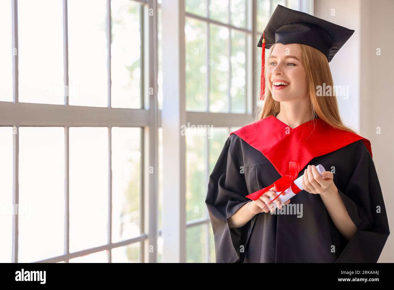 Female graduate student with diploma near window in room Stock Photo ...