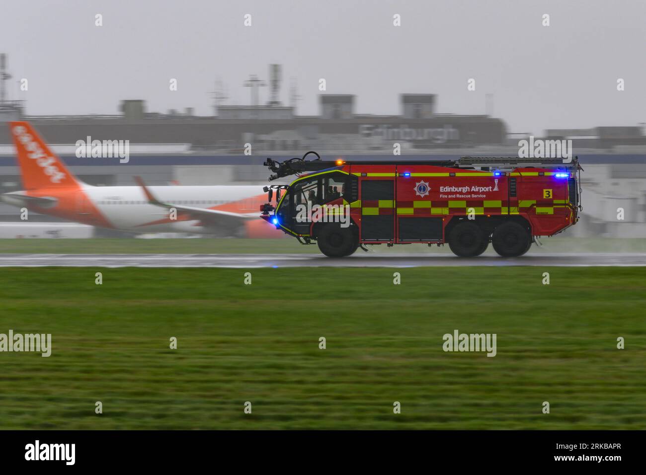 An Edinburgh Airport Fire Service Rosenbauer Panther Fire Truck Heads Down A Rain Soaked Runway During An Emergency Incident With A Qatar Airways A350 Stock Photo