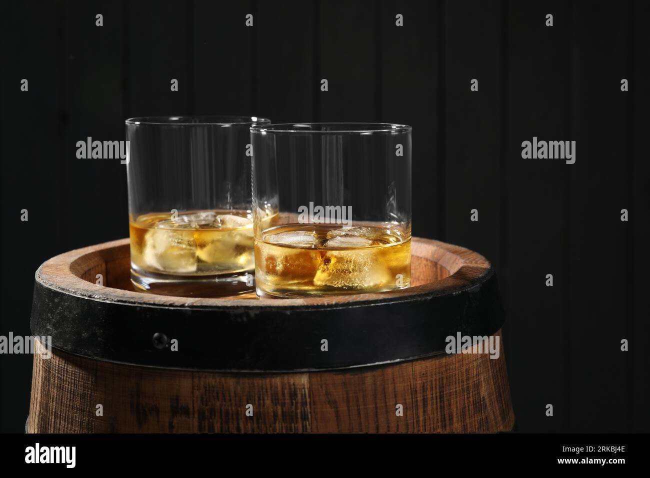 Glasses of tasty whiskey on wooden barrel Stock Photo