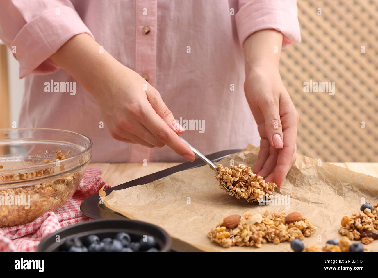 Making granola bars. Woman putting mixture of oat flakes, dry fruits