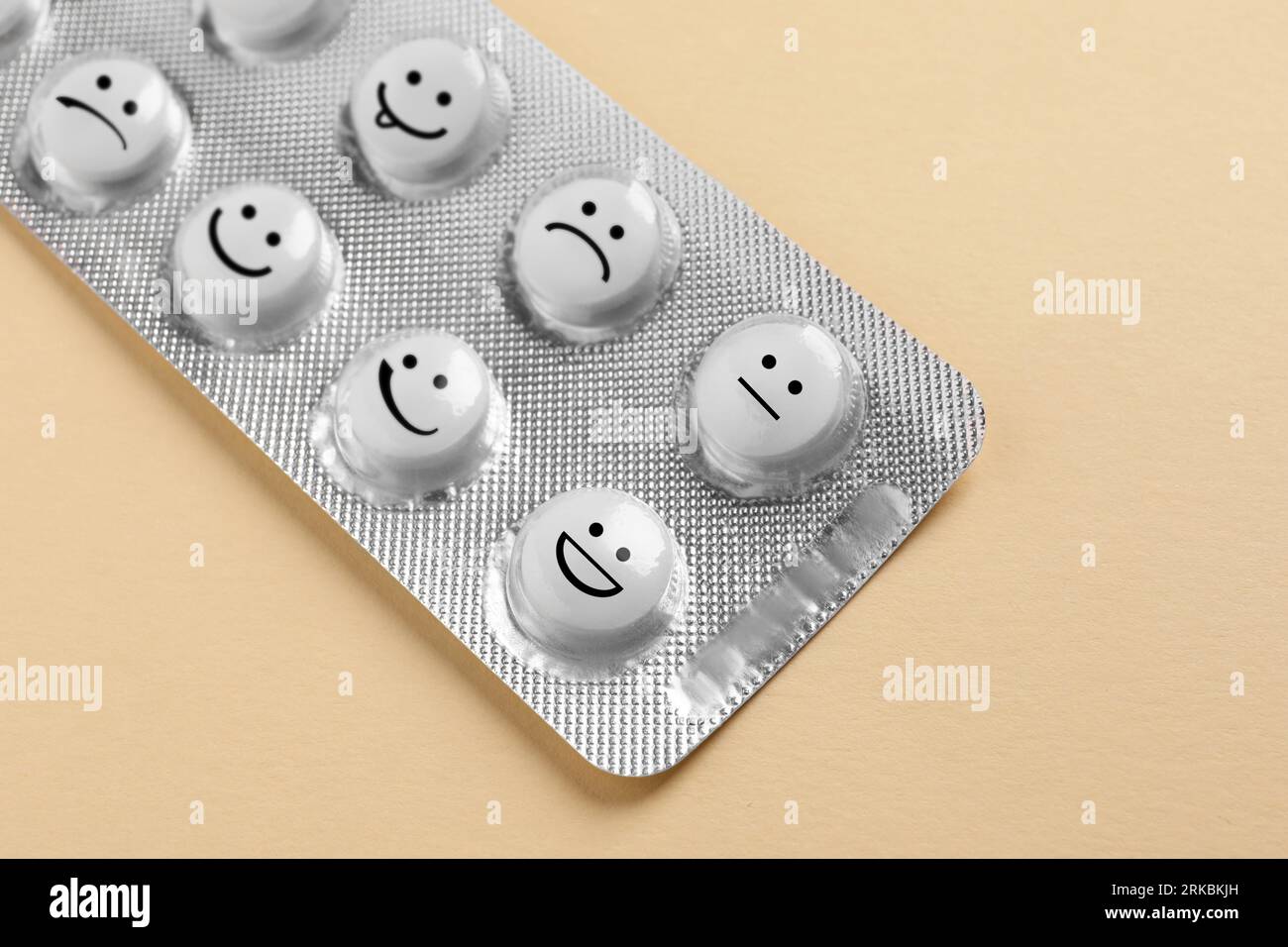 White pills with different emotional faces in blister on beige ...