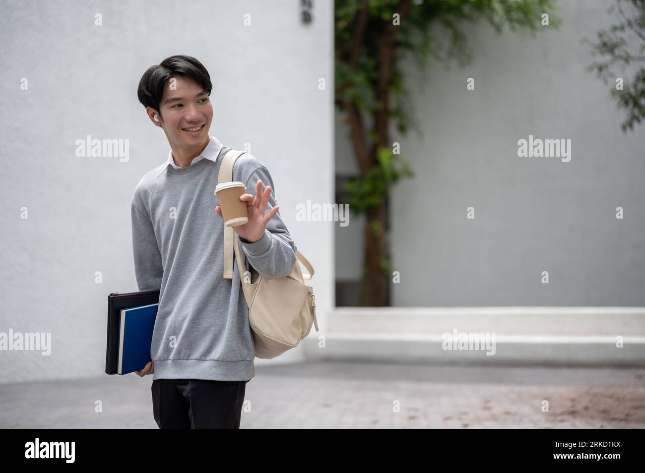 A handsome and smiling young Asian male student in casual clothes and ...