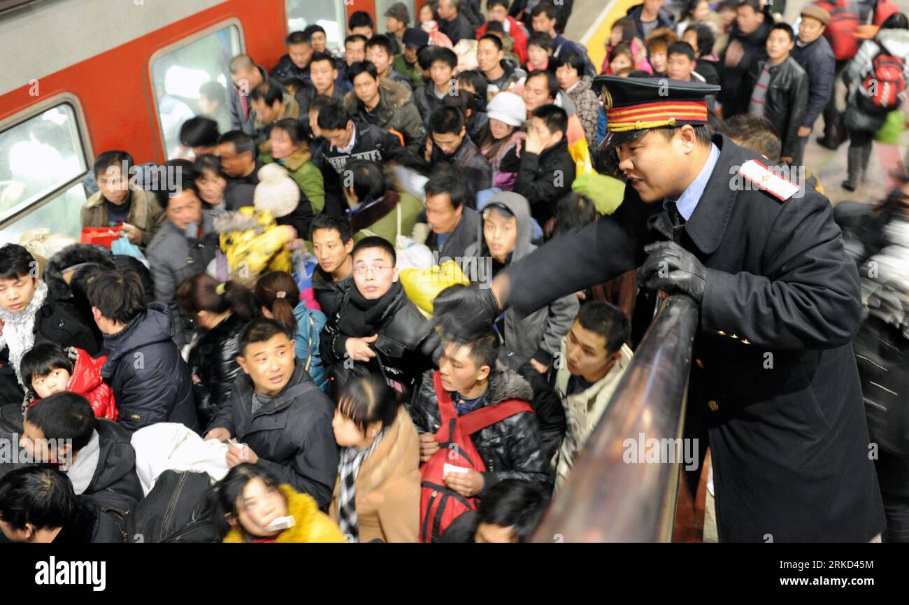 Bildnummer: 54858417  Datum: 27.01.2011  Copyright: imago/Xinhua (110127) -- BEIJING, Jan. 27, 2011 (Xinhua) -- Li Chao, a staff member of Beijing West Railway Station, show passengers the way to go aboard trains at a railway deck of the station in Beijing, capital of China, Jan. 25, 2011. Since China s 40-day period of Spring festival travel rush began on Jan. 19, all of the station s staff members have extended their labor time to more than 10 hours a day to ensure trains setting off and arriving on time with their passengers. The nationwide railway system transported 35, 886, 000 passengers Stock Photo