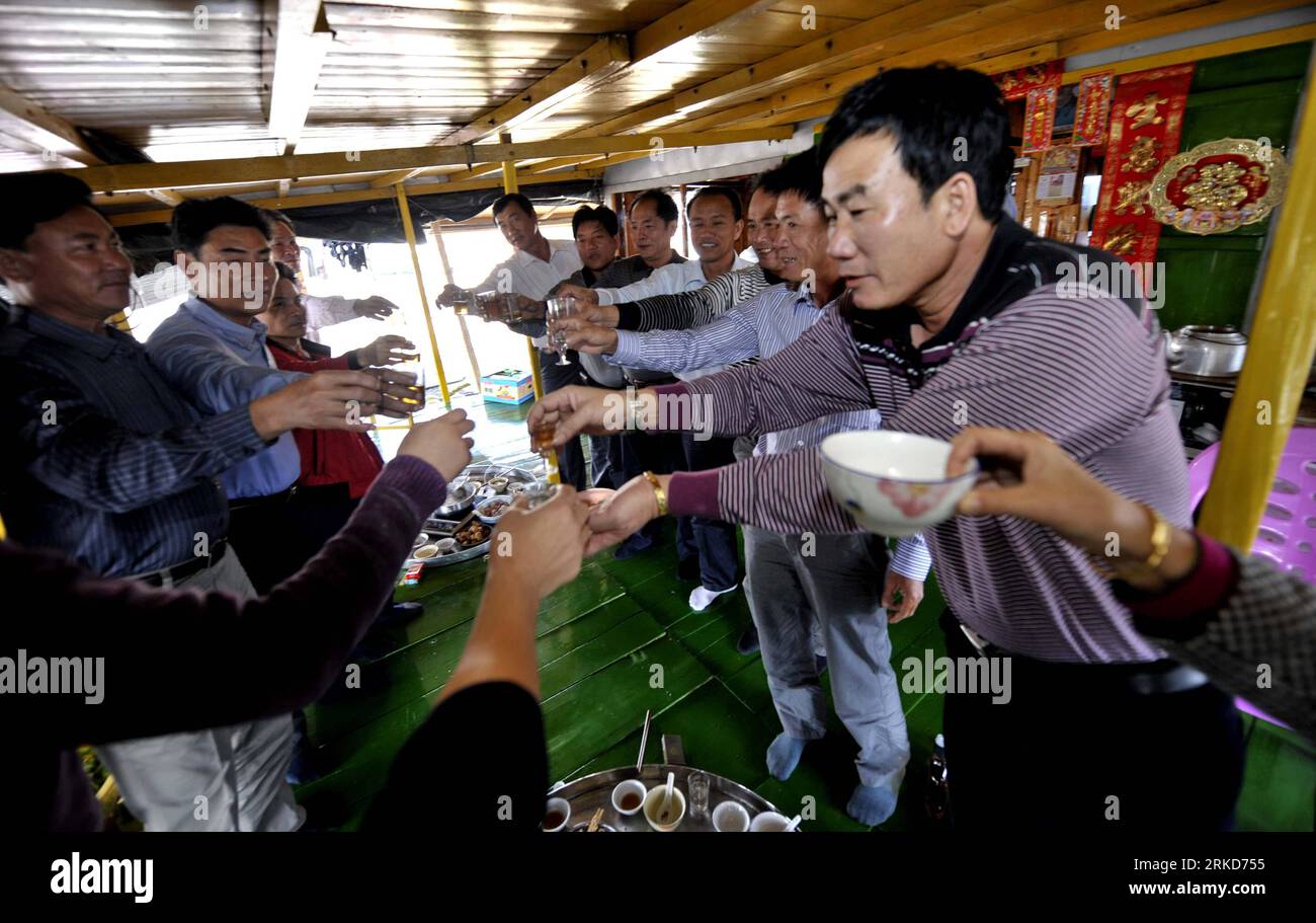 Bildnummer: 54878166  Datum: 03.02.2011  Copyright: imago/Xinhua (110203) -- LINGSHUI, Feb. 3, 2011 (Xinhua) -- Men of Danmin toast each other during a feast to mark the Spring Festival on a fishing boat in Lingshui, south China s Hainan Province, Feb. 3, 2011. Danmin take boats as their homes since they travelled from southeast China s Fujian and Guangdong provinces to set down here in the 17th century. Nowadays, some 12,000 Danmin still live in Hainan Province observing the tradition. (Xinhua/Hou Jiansen) (zn) CHINA-HAINAN-LINGSHUI-CHINESE NEW YEAR-DANMIN (CN) PUBLICATIONxNOTxINxCHN Gesellsc Stock Photo