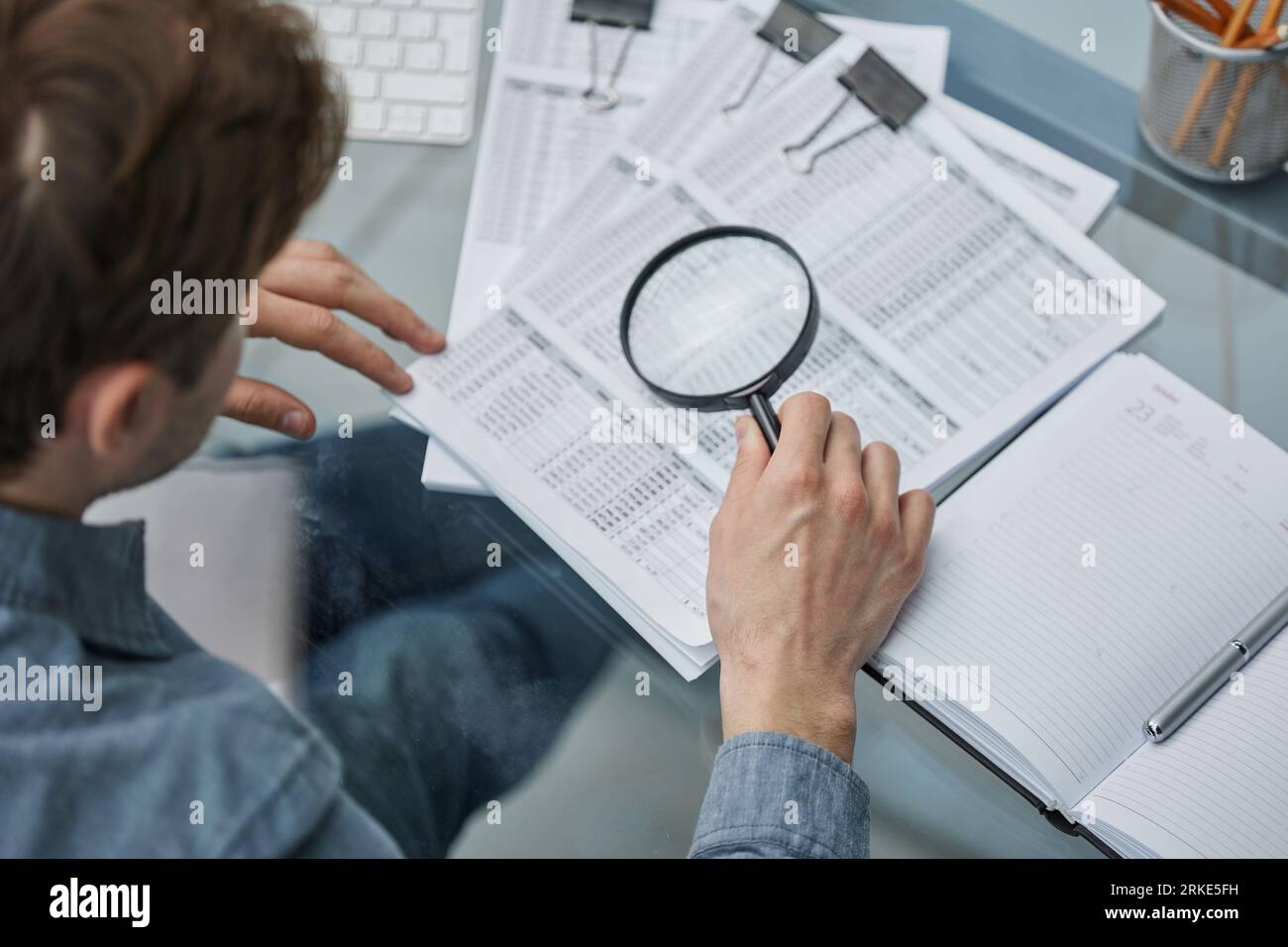 Look Over Notes Businessman looking through a magnifying glass to documents note in the ...