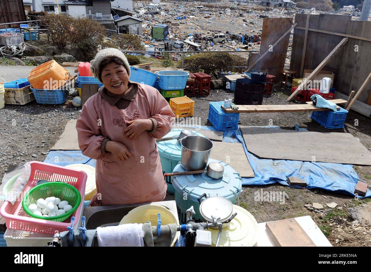 Bildnummer: 55055320  Datum: 23.03.2011  Copyright: imago/Xinhua (110323) -- MIYAGI, March 23, 2011 (Xinhua) -- Tamie Suda, 62, cooks meal in front of her house in Oshikacho of Miyagi prefecture, Japan, March 23, 2011. The Suda family survived from the quake-tsunami, but lost the source of income as the family hotel they run was destroyed. The family members began to rebuild houses although the water, gas and power supplies were cut off at present. (Xinhua/Song Zhenping) (lyi) JAPAN-MIYAGI-DAILY LIFE PUBLICATIONxNOTxINxCHN Gesellschaft Japan Naturkatastrophe Erdbeben Tsunami Schäden Alltag Lan Stock Photo