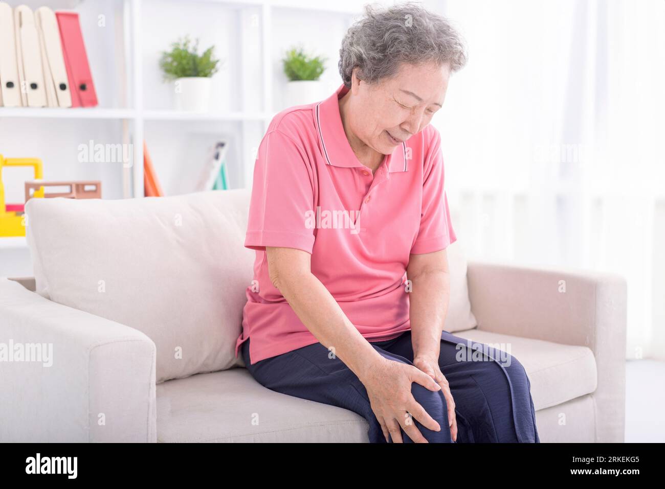 Asian senior woman sitting on sofa and having the joint pain Stock Photo