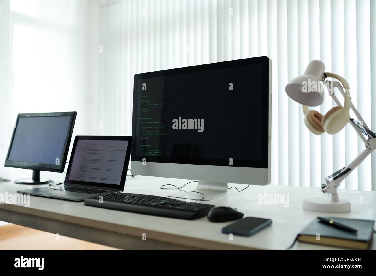 Computers and laptop with programming code on screens in office of it company Stock Photo