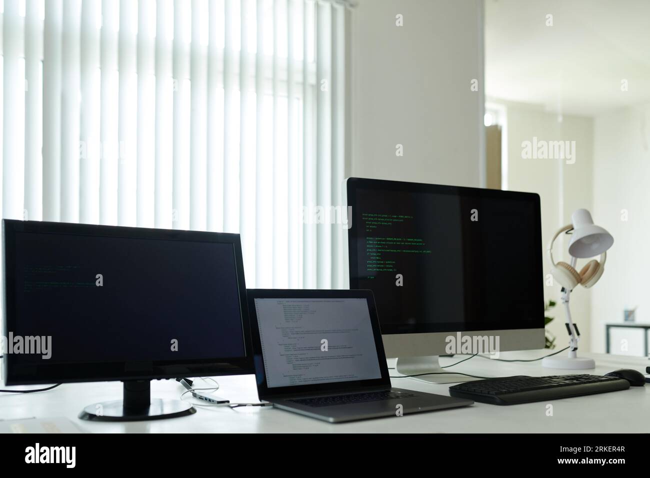 Laptop and computers with programming code on table in office Stock Photo