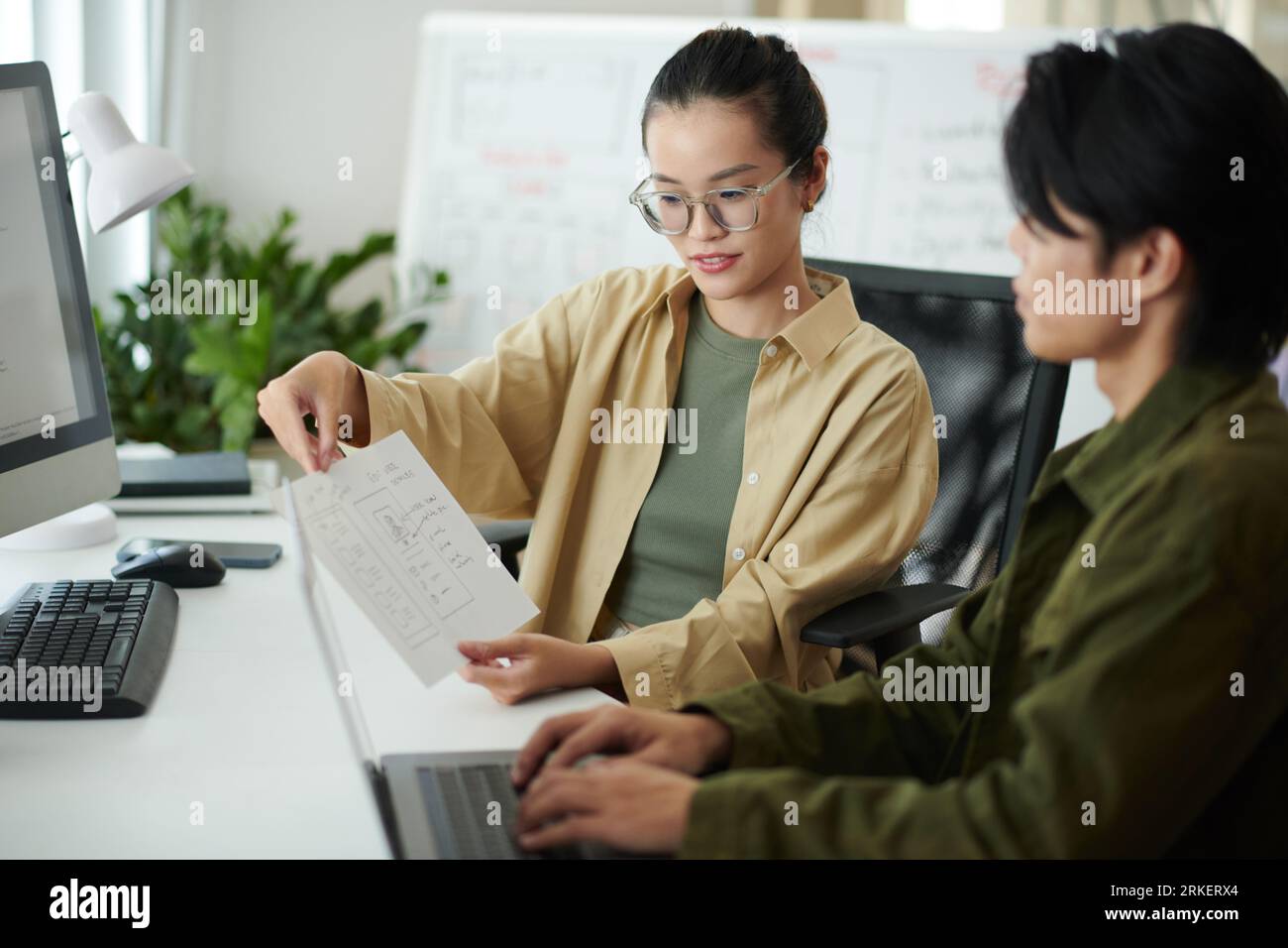 UI designer showing website wireframe to coworker Stock Photo