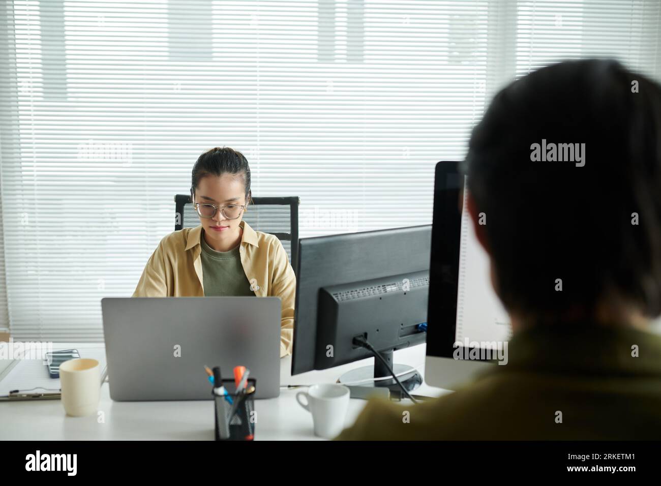 Pensive software developer working on laptop at office desk Stock Photo