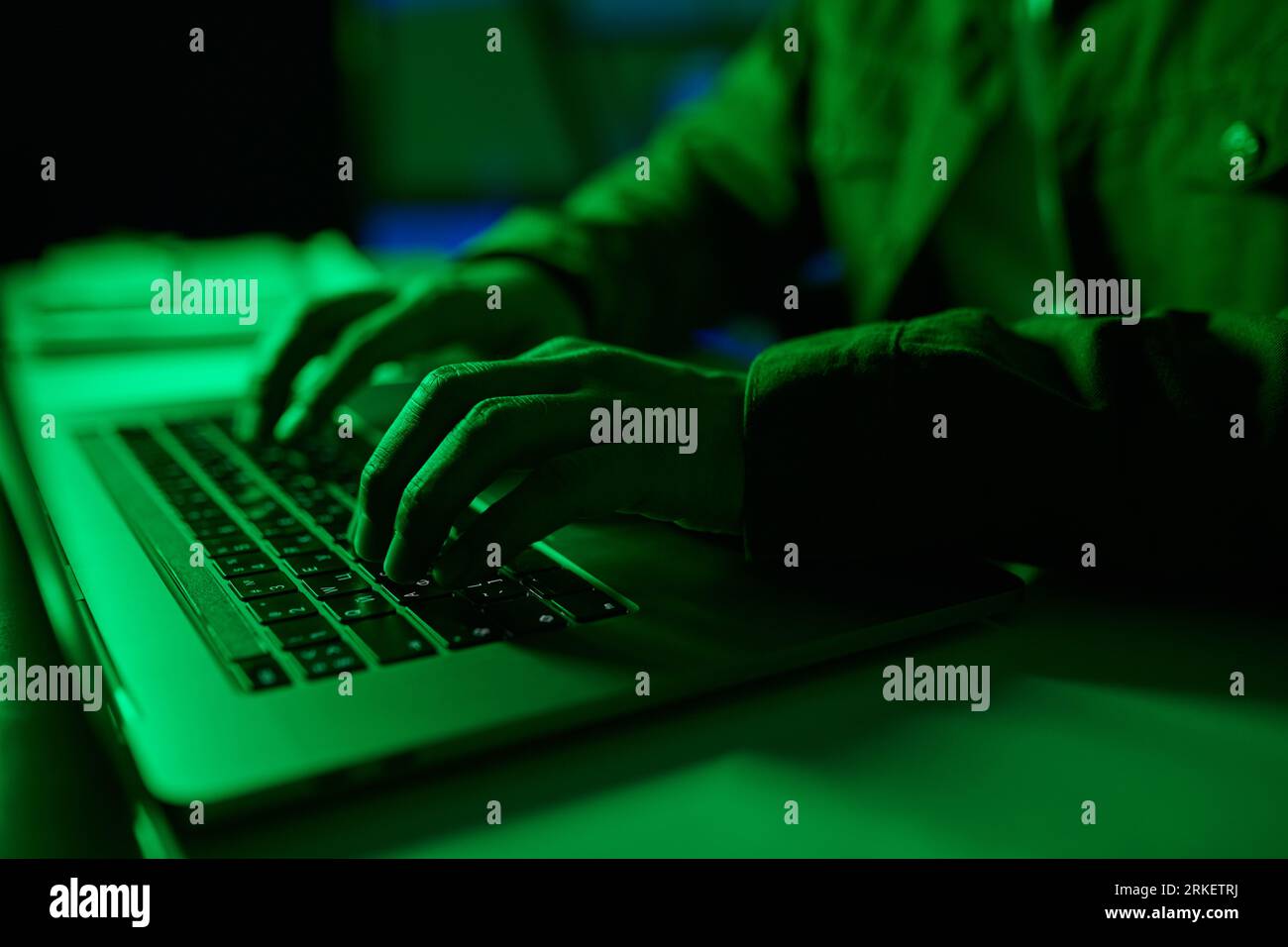 Closeup image of developer coding on laptop in green neon light Stock Photo