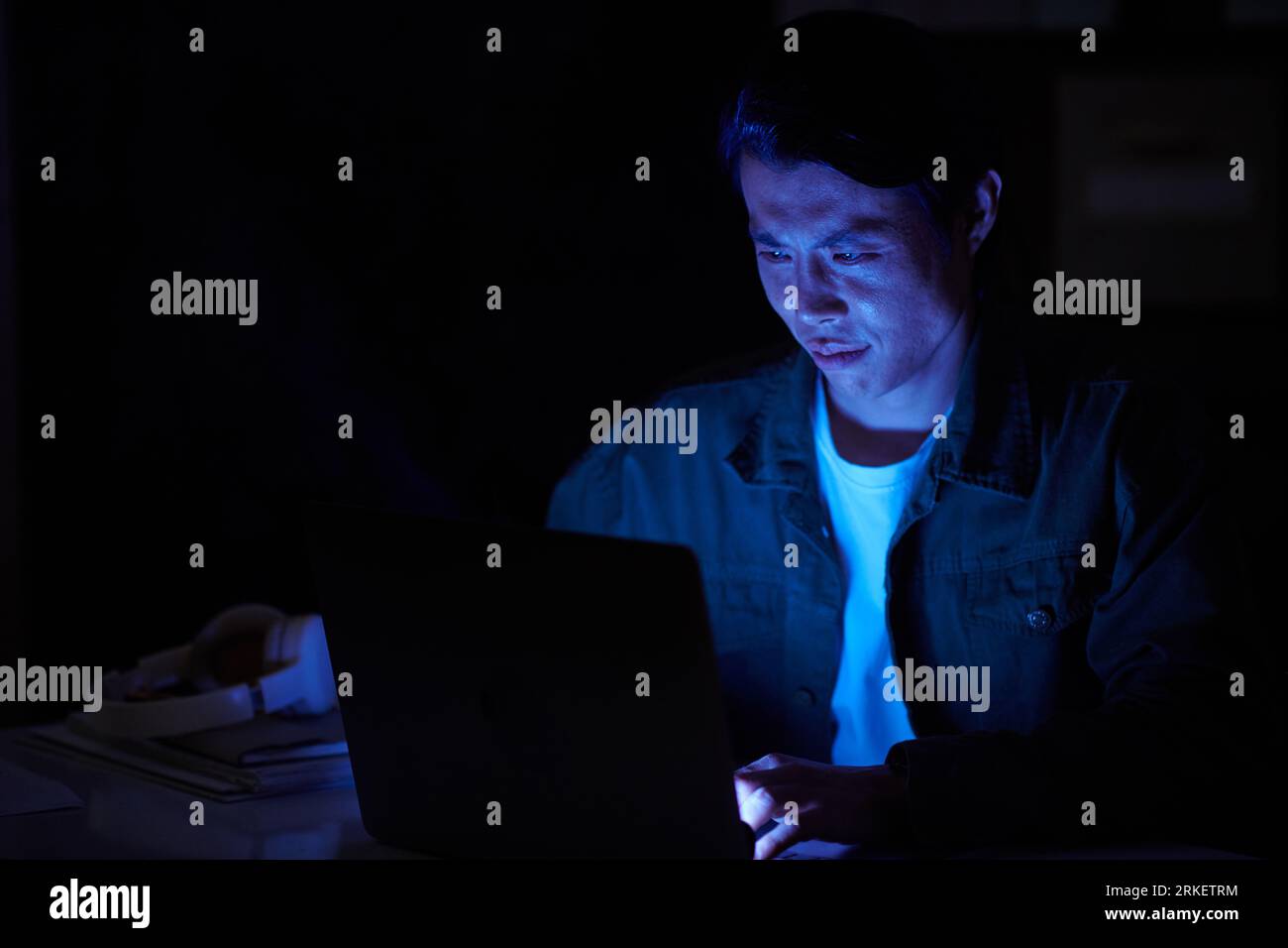 Software developer working in office late at night trying to handle work deadlines Stock Photo