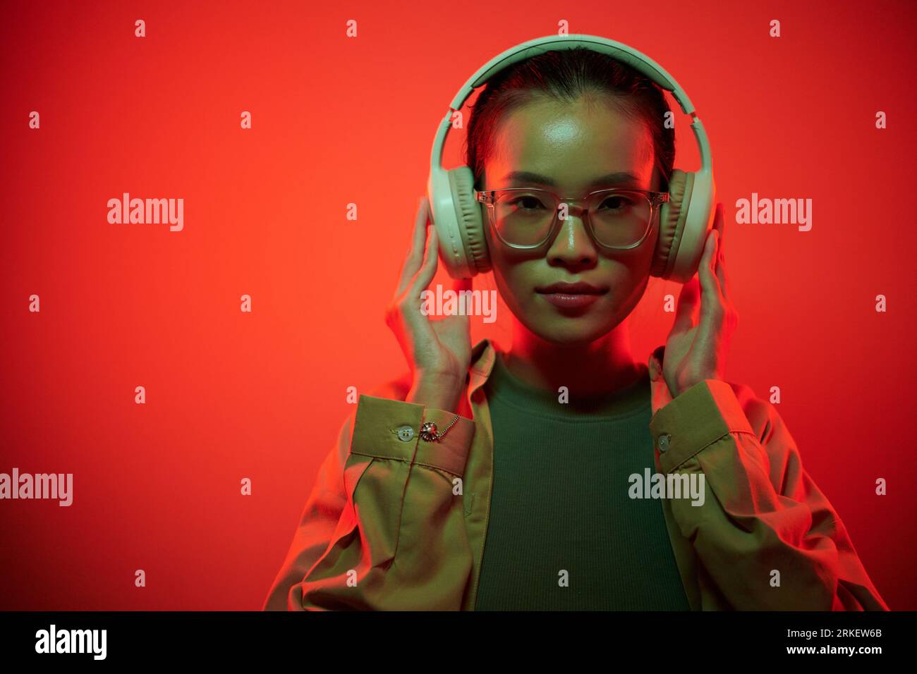 Portrait of young female gamer putting on headphones when getting ready for raid Stock Photo