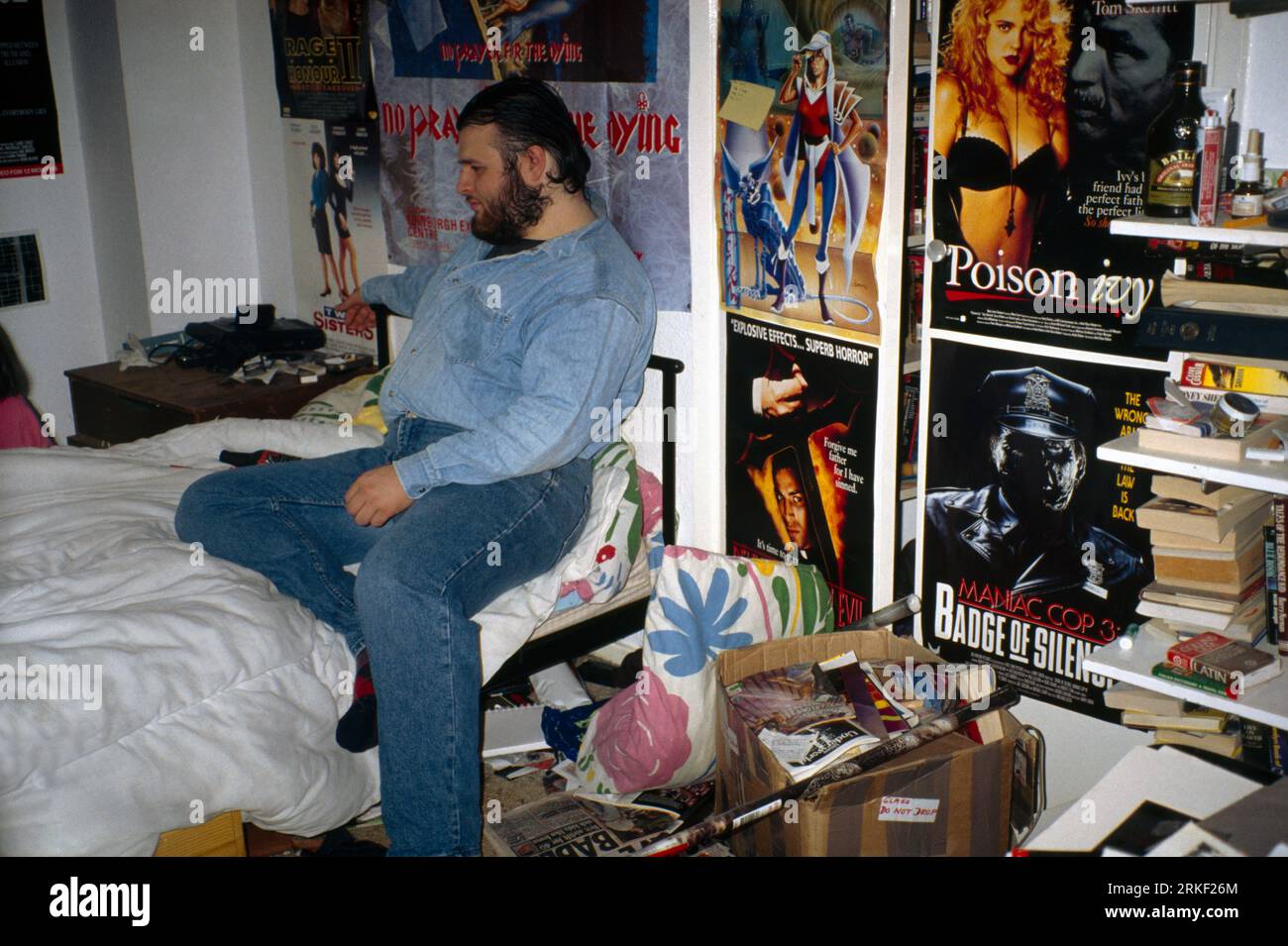 Overweight Teenage Boy in Messy Bedroom with  1990's Movie Posters on the Wall Surrey England Stock Photo