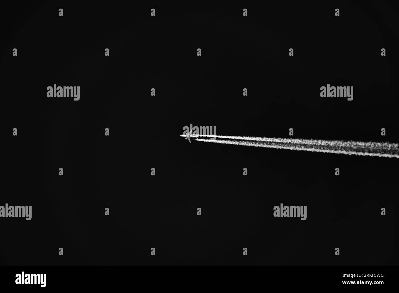 Airplane silhouette high up in the sky with fluffy vapor trail isolated